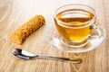 Creamy-peanut sausage, cup with tea on saucer, spoon on wooden table