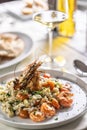 Creamy risotto with orange shrimps and zucchini served with white wine in a restaurant