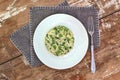 Creamy risotto with peas and spinach on white plate on grey cloth on rustic table