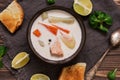 Creamy salmon soup with potatoes and carrots served with toast on a wooden rustic plank table. Finnish fish soup kalakeitto with