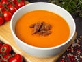 Creamy tomato soup of rich color with vegan jerks in a bowl on a wooden board. Cherry tomatoes, pink pepper and Himmalay salt Royalty Free Stock Photo