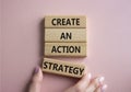 Create an action Strategy symbol. Wooden blocks with words Create an action Strategy. Beautiful pink background. Businessman hand