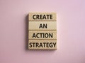 Create an action Strategy symbol. Wooden blocks with words Create an action Strategy. Beautiful pink background. Businessman hand