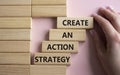 Create an action Strategy symbol. Wooden blocks with words Create an action Strategy. Beautiful pink background. Businessman hand