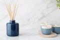 Create a serene atmosphere with navy blue reed diffuser and soft beige candles on marble Royalty Free Stock Photo