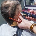 Creating a close-up of a mans haircut, a hairdresser cuts his hair with a haircut and a comb. Barber shop concept