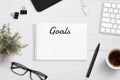 Creating goals list on notepad on office desk surrounded with office supplies