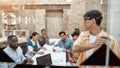 Creating new business strategy. Young asian man writing something at white blackboard and looking at his colleagues Royalty Free Stock Photo