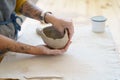 Creating pottery: table in ceramic studio with master hands shaping clay pot. Woman potter sculpting