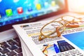 Stack of newspapers on laptop and eyeglasses