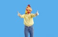 Cheerful funny and humorous woman in rubber mask of chicken shows thumbs up on blue background. Royalty Free Stock Photo