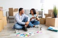 Creative african american spouses working on design for their house, discussing color palette while sitting among boxes Royalty Free Stock Photo