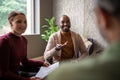 Creative african businessman smiling and chatting casually with fellow diverse coworkers