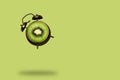 Creative art collage flying alarm clock with kiwi fruit slice on a green background, summer bright poster