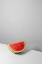 Creative art composition of a piece of ripe watermelon lies on the edge of the table. Vertical photo orientation