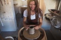 Female artisan creatively sculpting wet clay on a pottery wheel