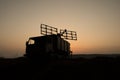 Creative artwork decoration. Silhouette of mobile air defence truck with radar antenna during sunset. Satellite dishes or radio Royalty Free Stock Photo