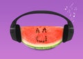 Creative artwork. Watermelon listening to music in headphones on magenta background. Slice of fruit with drawings, eyes and smile Royalty Free Stock Photo