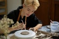 A creative Asian gay man pottery artist holding a sculpting tool, making patterns on raw clay Royalty Free Stock Photo