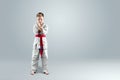 Creative background, a child in a white kimono in a fighting stance, on a light background Royalty Free Stock Photo