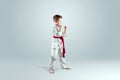 Creative background, a child in a white kimono in a fighting stance, on a light background Royalty Free Stock Photo