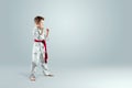 Creative background, a child in a white kimono in a fighting stance, on a light background Royalty Free Stock Photo