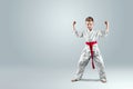 Creative background a child in a white kimono in a fighting stance, on a light background The concept of martial arts Royalty Free Stock Photo