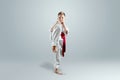 Creative background, a child in a white kimono makes a kick, on a light background. The concept of martial arts, karate
