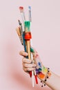 Creative background. Female artist hand holding colorful paintbrushes. Paints and brushes background. Art class, art school. Pink