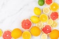 Creative background made of summer tropical fruits with grapefruit, orange, tangerine, lemon, lime on white marble background.