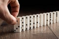 Creative background, Male hand pushing white dominoes, on a brown wooden background. Concept of domino effect, chain Royalty Free Stock Photo