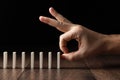 Creative background, Male hand pushing white dominoes, on a brown wooden background. Concept of domino effect, chain Royalty Free Stock Photo