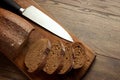 Creative background, sliced rye bread and a knife close-up, on a wooden cutting board, flat lay, copy space. The concept Royalty Free Stock Photo