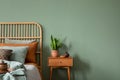 Creative bedroom interior composition with boho style bed, night table, home decorations and personal accessories. Eucalyptus wall Royalty Free Stock Photo