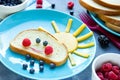 Creative breakfast idea for kids - bread bun with fruit and berry shaped funny cloud with peach sun and blueberry rain Royalty Free Stock Photo