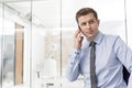 Confident businessman looking away while using smartphone in office Royalty Free Stock Photo