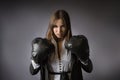 Creative business portrait of a woman in an office suit with boxing gloves. Gray background Royalty Free Stock Photo