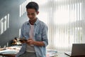 Creative business. Portrait of young asian man using touchpad while leaning on a table in the modern office. Focused Royalty Free Stock Photo