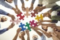 Bottom view of team of creative business people connecting pieces of jigsaw puzzle Royalty Free Stock Photo