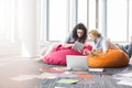 Creative businesswomen using tablet PC while relaxing on beanbag chairs at office