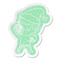 A creative cartoon distressed sticker of a grumpy boy wearing santa hat