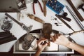 Creative chaos. Top view of jeweler`s workbench with different tools for making jewelry. Female jeweler`s hands