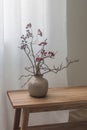 Creative Christmas bouquet decor in a ceramic vase on a wooden bench. Cozy home interior