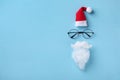 Creative Christmas composition. Greeting card, invitation or flyer. Santa hat, beard and glasses on blue background