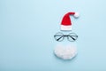 Creative christmas composition. Greeting card, invitation or flyer. Santa hat, beard and glasses on blue background top view.