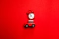 Creative christmas concept of red alarm clock round clock and toy car model on red background, top view. Minimal creative holiday Royalty Free Stock Photo