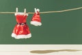 Creative Christmas layout with a clean red Santa Claus suit and hat dries on a rope against a green background. Minimal Xmas or Royalty Free Stock Photo