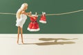 Creative Christmas layout with a doll wearing a towel and a clean red Santa Claus suit and hat against a green background. Minimal Royalty Free Stock Photo