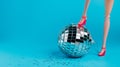 Creative Christmas party composition with doll leg in high heels and shiny disco ball on blue background. Minimal Xmas or New Year Royalty Free Stock Photo