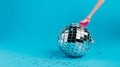 Creative Christmas party composition with doll leg in high heels and shiny disco ball on blue background. Minimal Xmas or New Year Royalty Free Stock Photo